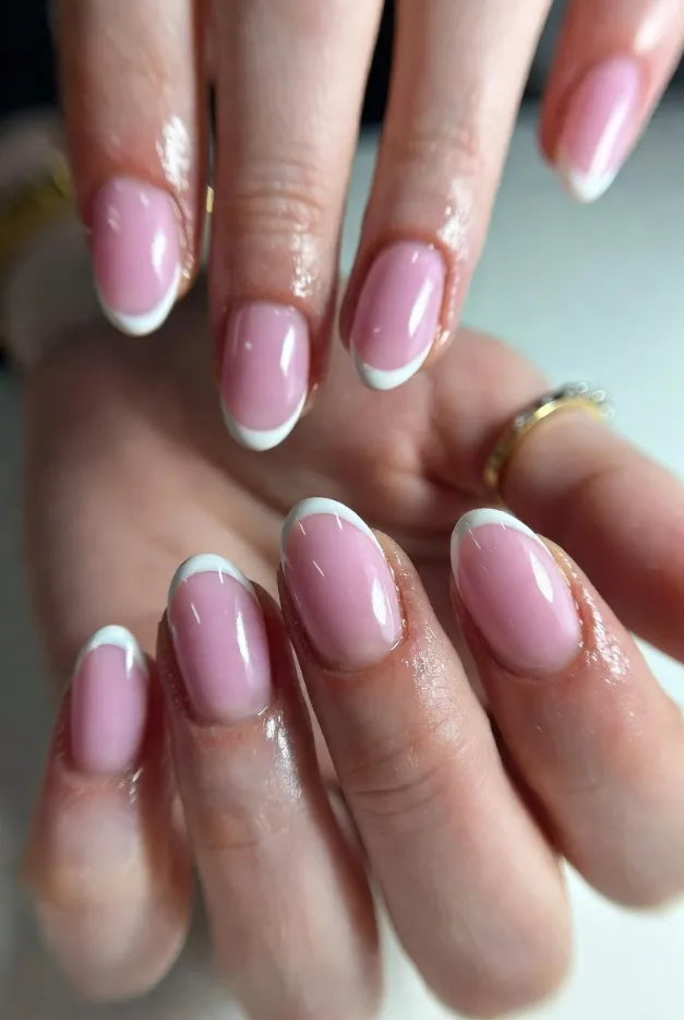 Glossy milky pink summer French tip nails 2026 with clean white oval tips and a soft natural base for an elegant everyday manicure.