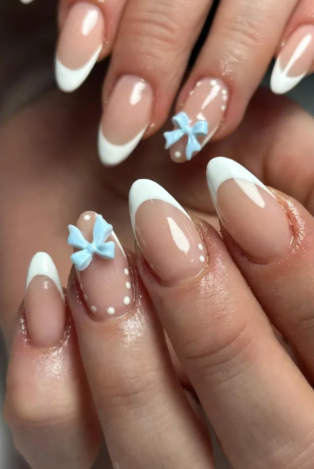 Coquette bow French tip nails with blue and white accents for a cute feminine summer manicure.