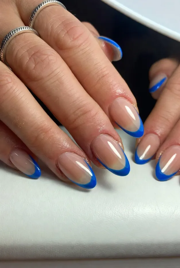 Blue summer French tip nails 2026 with glossy almond shape and sheer nude base for a fresh coastal manicure.