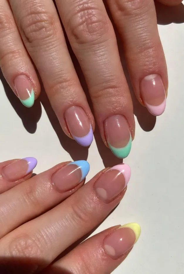 Pastel rainbow French tip nails with a glossy pink base, a colorful summer French manicure idea for 2026.