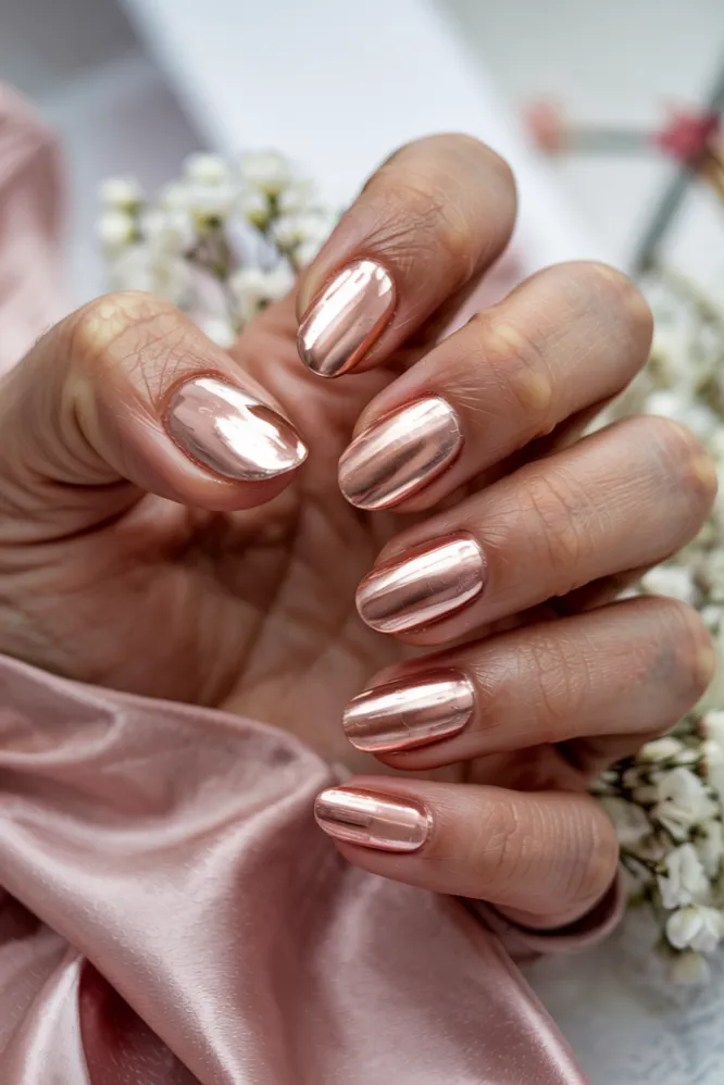 Rose gold chrome nail ideas on almond-shaped nails with soft pink metallic sheen and peachy base